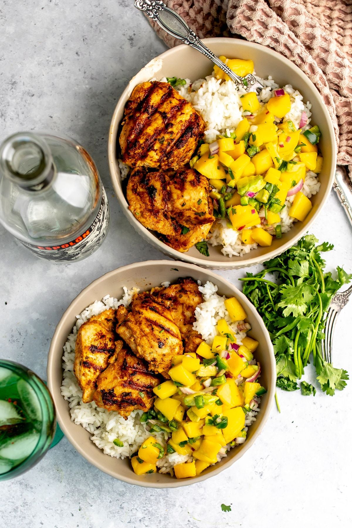 Ceramic bowl with tequila lime chicken thighs served over rice with mango salsa.