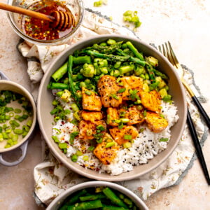 Ceramic bowl with hot honey salmon bites over rice with crispy asparagus and avocado.