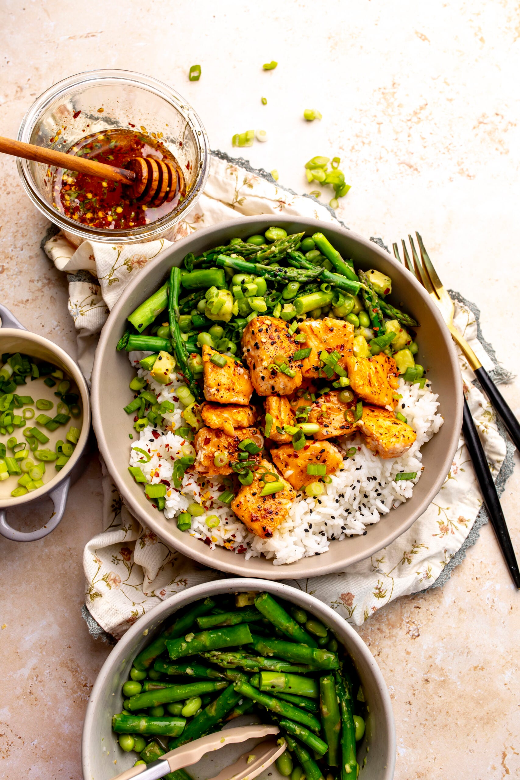 Ceramic bowl with hot honey salmon bites over rice with crispy asparagus and avocado.
