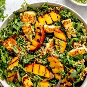 Peach and Halloumi Salad served in a ceramic bowl with pesto to the side.