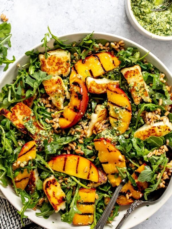 Peach and Halloumi Salad served in a ceramic bowl with pesto to the side.