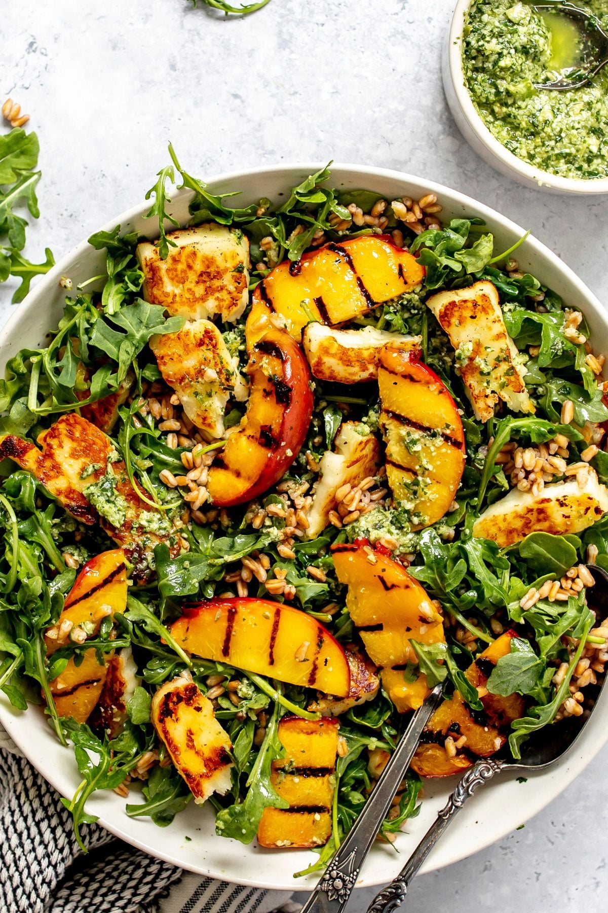 Peach and Halloumi Salad served in a ceramic bowl with pesto to the side.