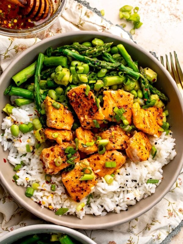 Ceramic bowl with hot honey salmon bites over rice with crispy asparagus and avocado.