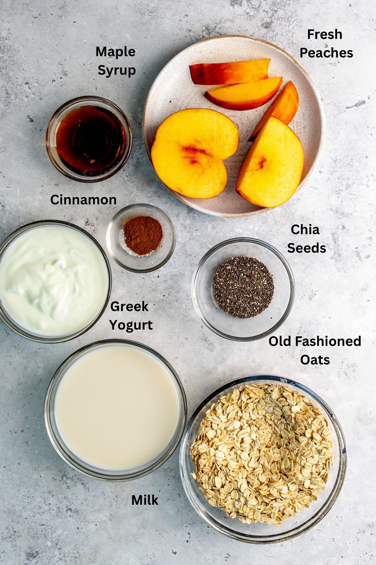 All of the ingredients for peach overnight oats in bowls on a countertop.