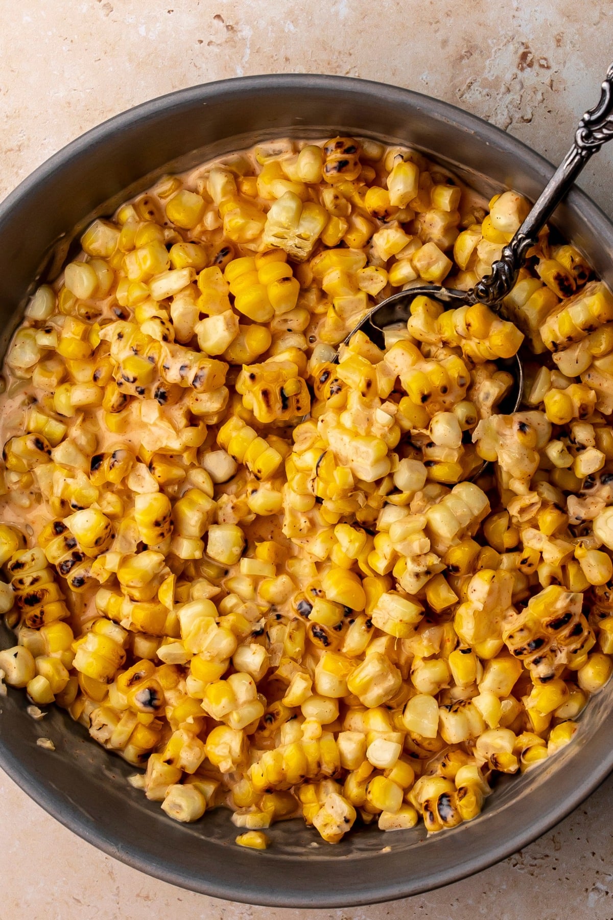 Grey bowl with creamy corn dressed in sauce.