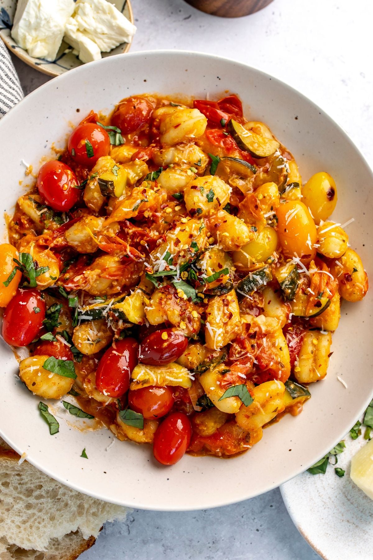 blistered tomato pasta gnocchi in a white bowl with basil on top.