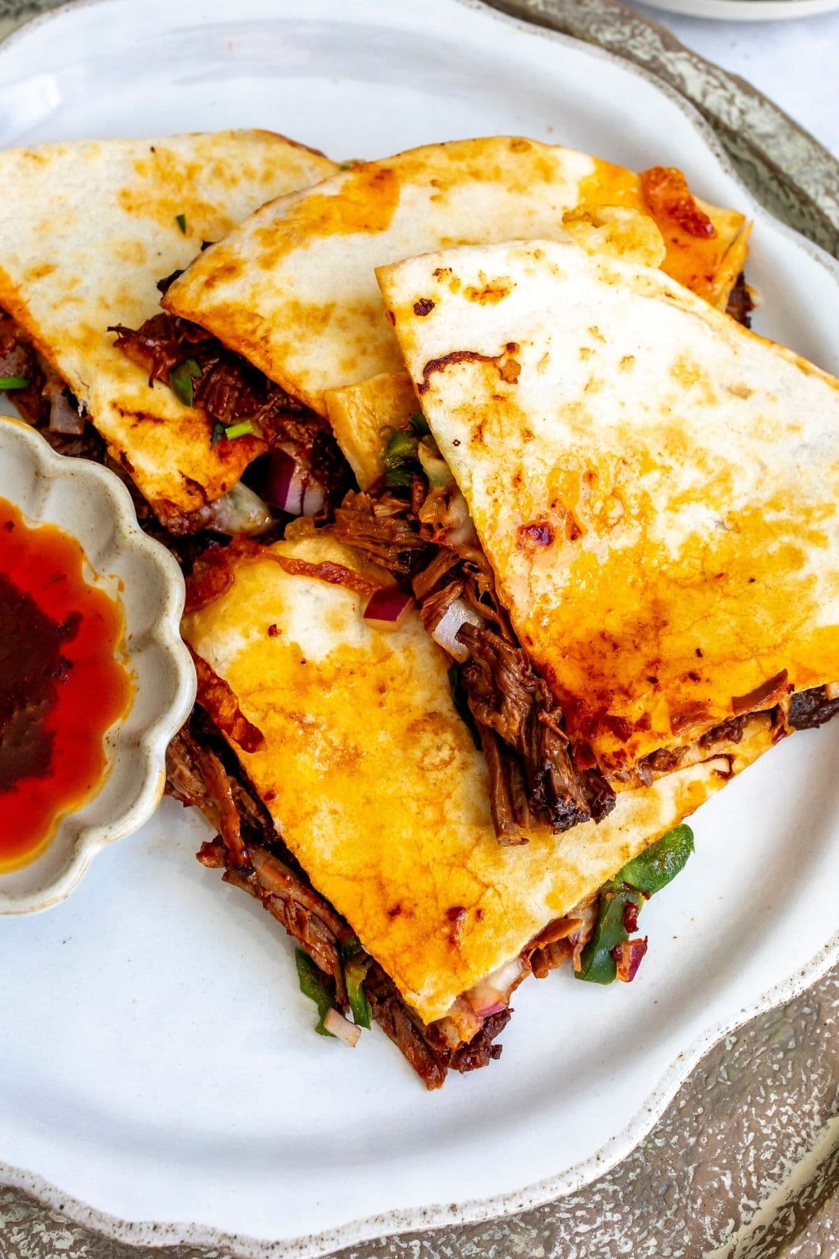 The four slices of birria quesadilla on a white plate for serving.