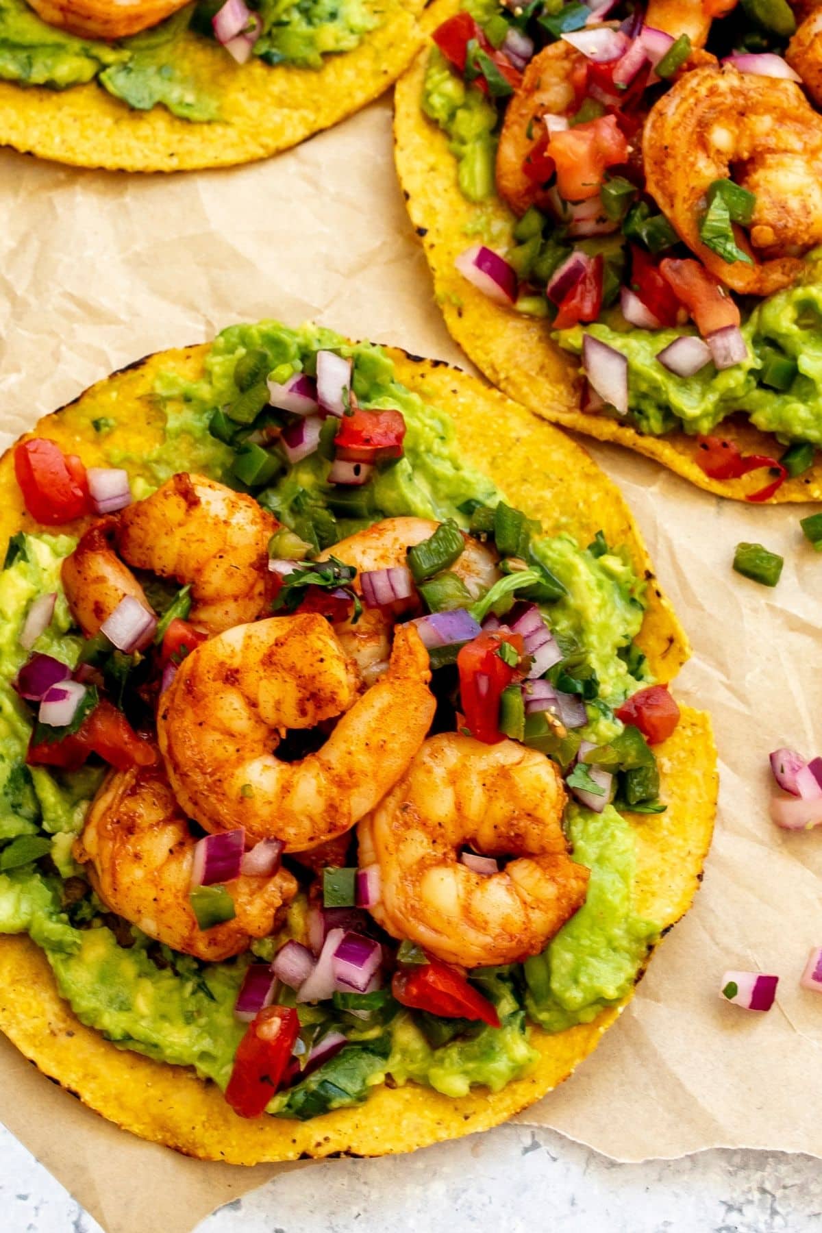 A shrimp tostada layered with guacamole, shrimp, and pico.