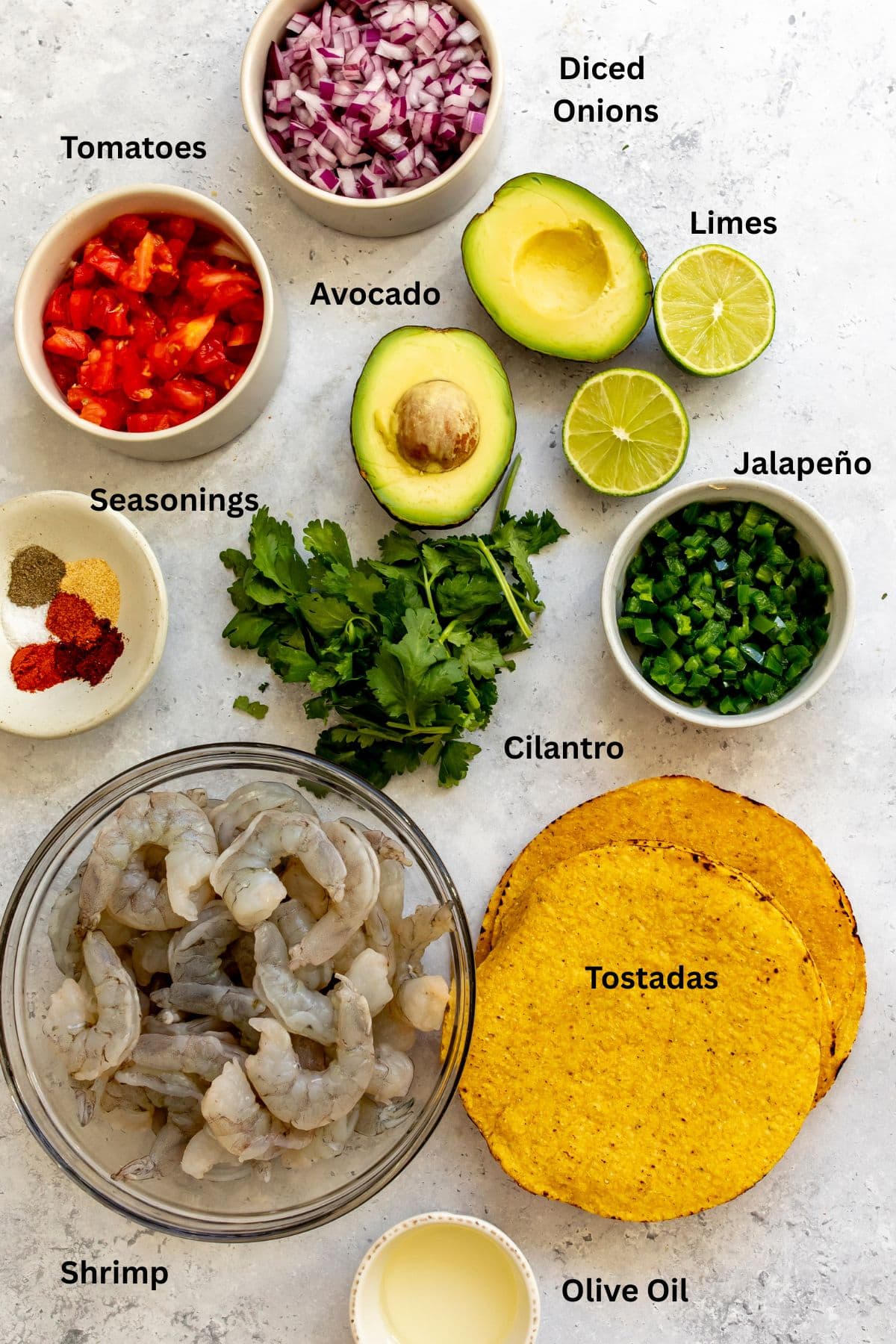All of the ingredients for shrimp tostadas in bowls on a countertop.
