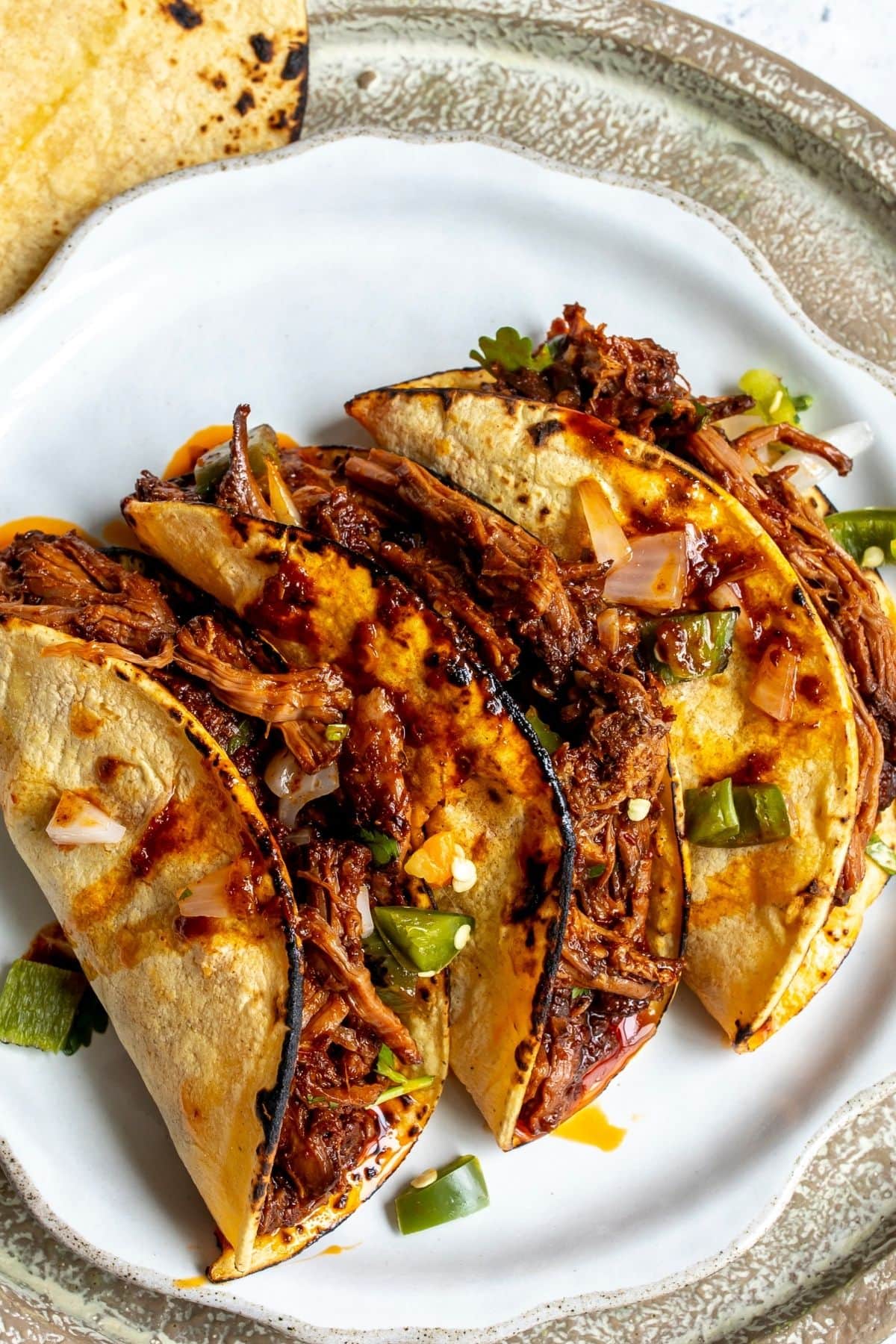 Three birria tacos on a white plate for serving.