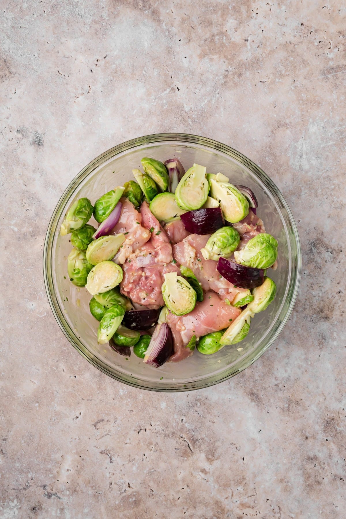 The brussels sprouts and chicken thighs toss together with the olive oil, salt, and pepper before adding to the sheet pan for baking.