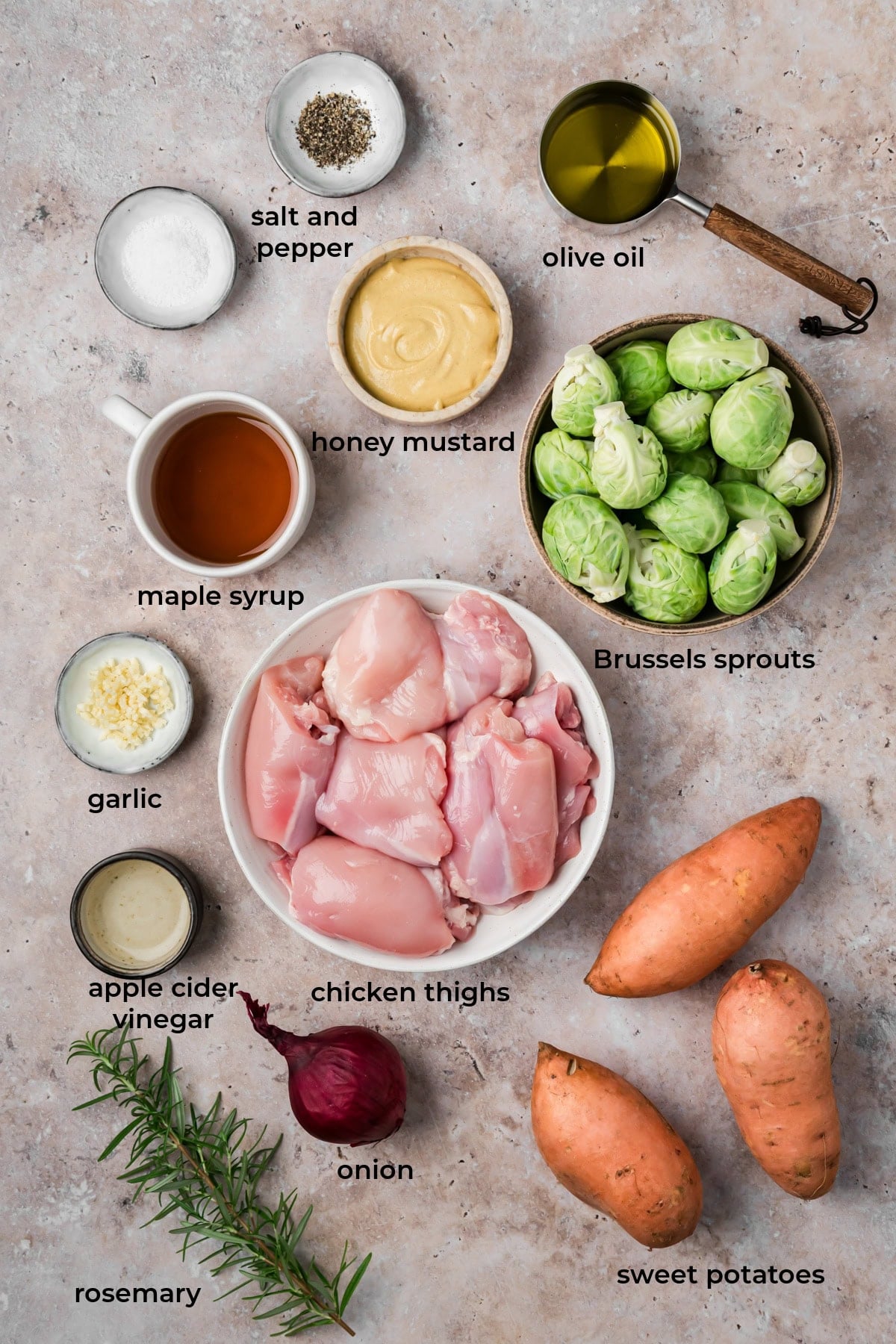 All of the ingredients for maple dijon sheet pan chicken thighs and vegetables in bowls on a countertop.