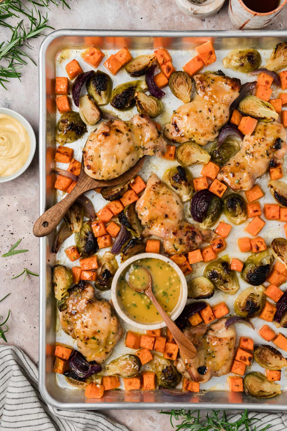 Maple dijon sheet pan chicken thighs on a sheet pan with roasted sweet potatoes and brussels sprouts.