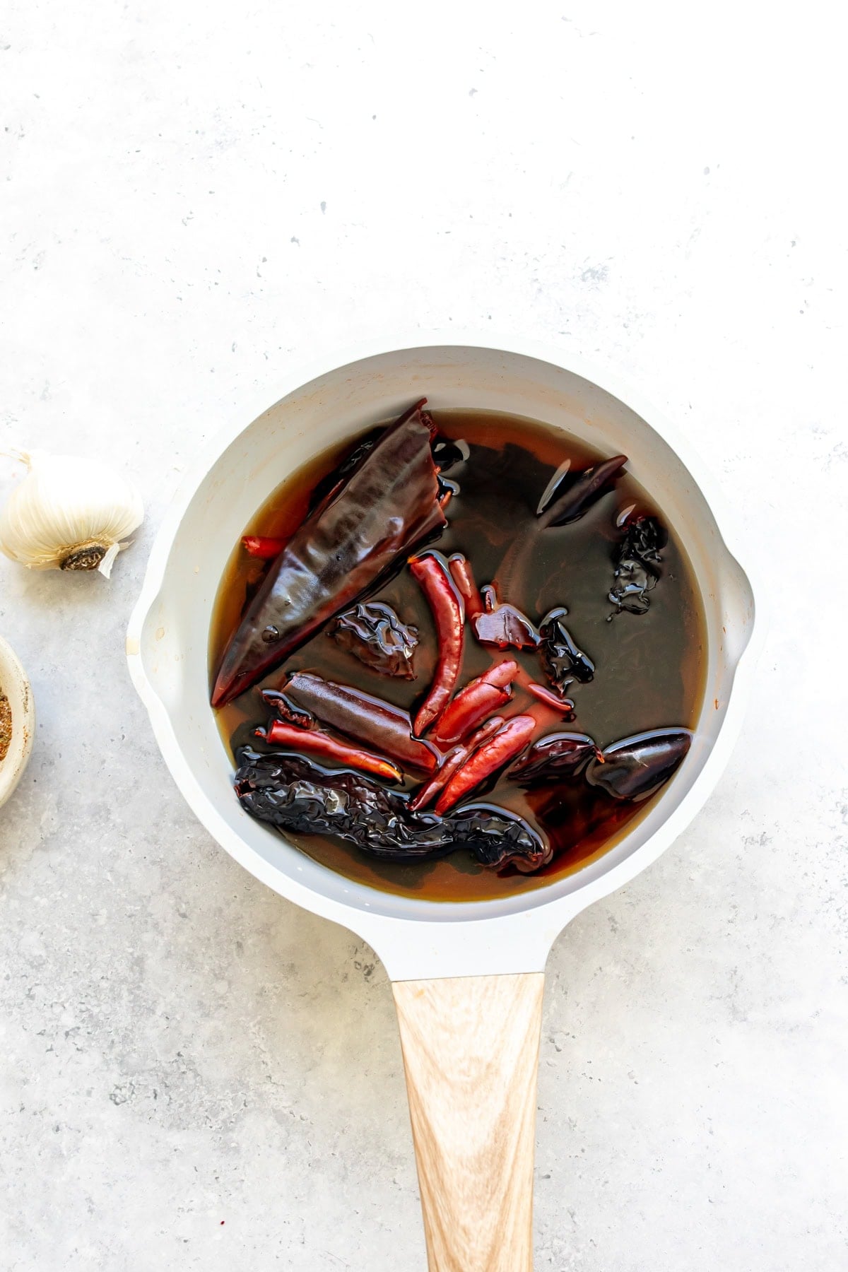 The chiles soaking in hot water in a saucepan.
