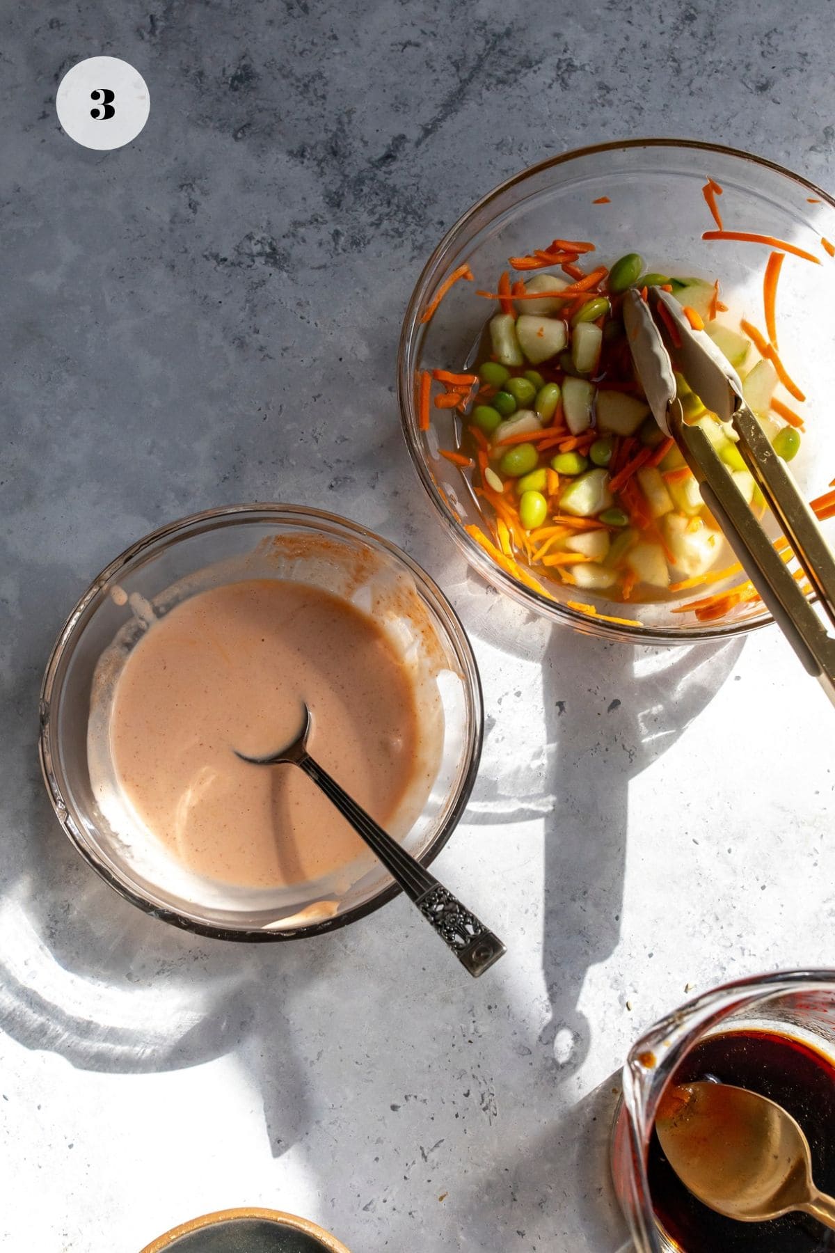 Bowls with pickled cucumber salad and spicy mayo in them separated.