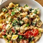Ceramic bowl with feta cheese chicken bake in it, topped with parsley and a silver fork to the side.