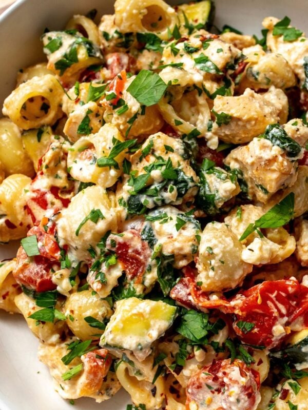 Ceramic bowl with feta cheese chicken bake in it, topped with parsley and a silver fork to the side.