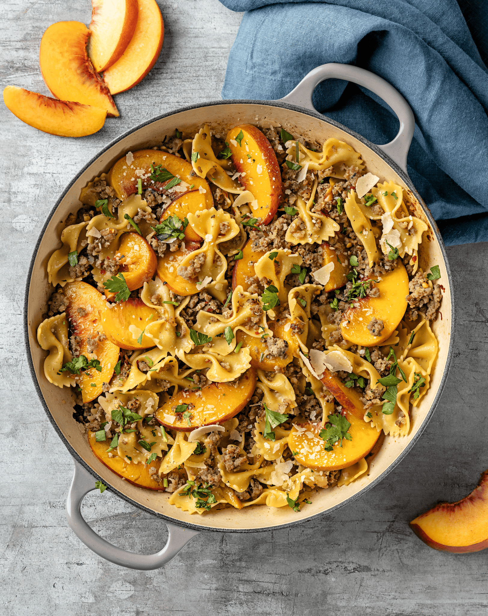 Peach sausage pasta in a large skillet on a countertop.