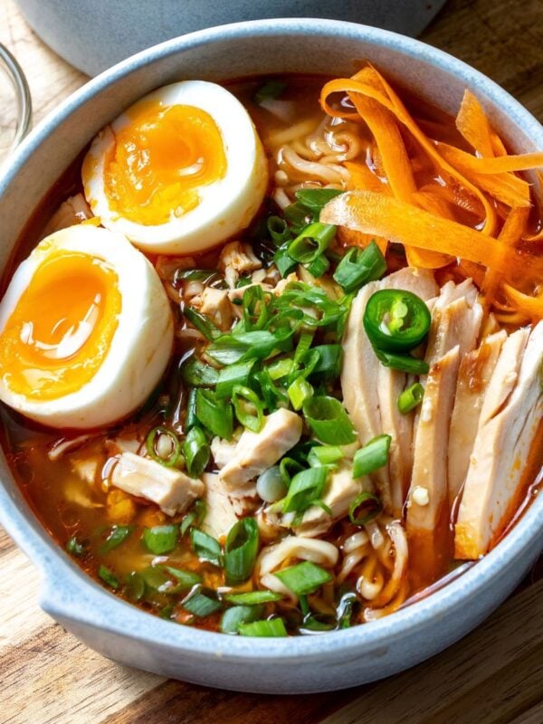 Spicy Chicken Ramen in broth served in white grey bowls with toppings.
